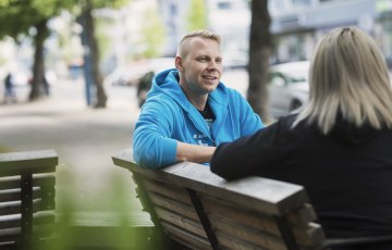 Henkilöt juttelevat puistonpenkillä