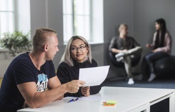 Mies ja nainen istuvat pöydänääressä ja keskustelevat 