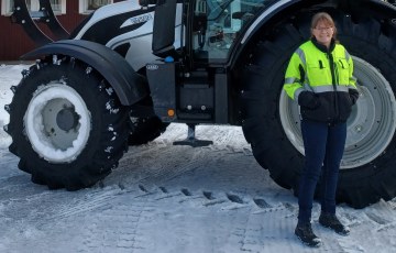 Nainen seisoo traktorin edessä talvella