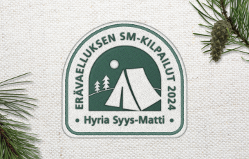 Syysmatti-logo. Logossa väreinä tummanvihreä ja beige. Logossa on kuvituksena beige teltan kuva tummanvihreällä taustalla. 