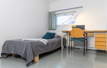 Valokuva Hyrian opiskelija-asuntolasta sisäpuolelta. Valokuvassa on vasemmalla sänky ja oikealla työpöytä.