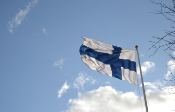 Suomen lippu liehuu taivasta vastan
