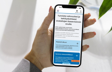 Henkilö pitelee kännykkää kädessään. Ruudulla näkyy Urataidot-työkalu Osaamispolku-palvelussa.