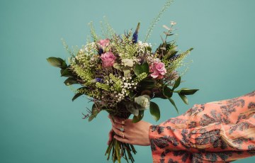 Kukkakimppu ja sitä ojentavat kädet