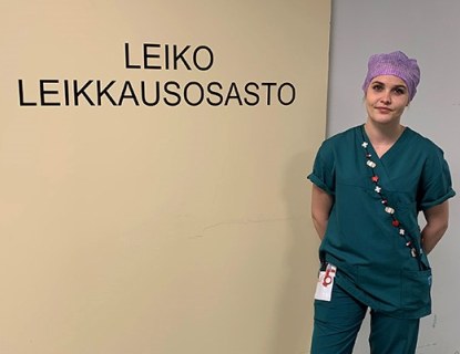 Instrumenttihoitaja työvaatteissa leikkausosaston oven edessä Hyvinkään sairaalassa