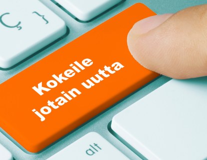 Lähikuva, jossa henkilö painaa tietokoneen näppäintä, jossa teksti "kokeile jotain uutta"