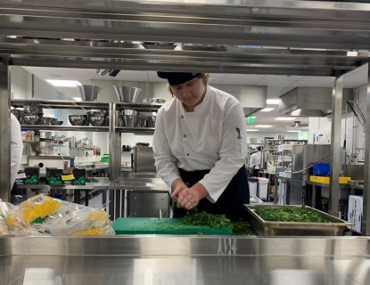 Kokkiopiskelija pilkkoo lehtipersiljaa opetuskeittiössä