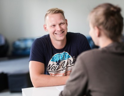 kaksi ihmistä istuu vastakkain pöydän ääressä