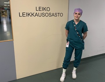 Instrumenttihoitaja työvaatteissa leikkausosaston oven edessä Hyvinkään sairaalassa